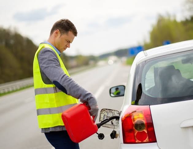 Fuel being poured from a red fuel can into a vehicle